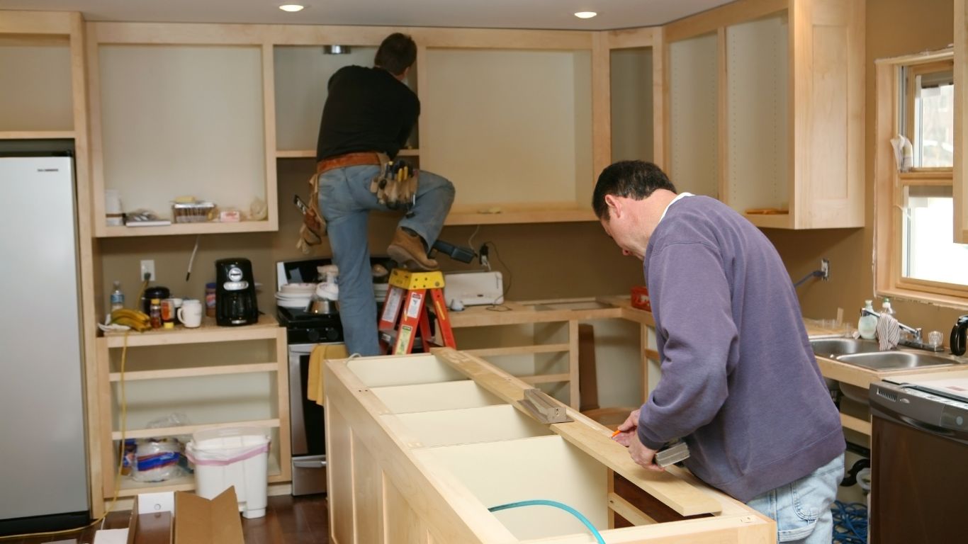 Residential remodels in progress showing craftsmen installing custom kitchen cabinets during a home renovation.